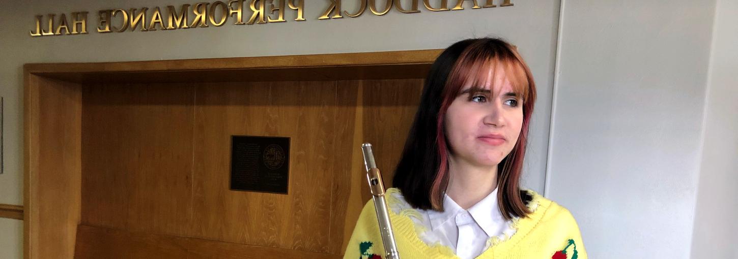 一名女子手持长笛站在音乐学校的走廊上